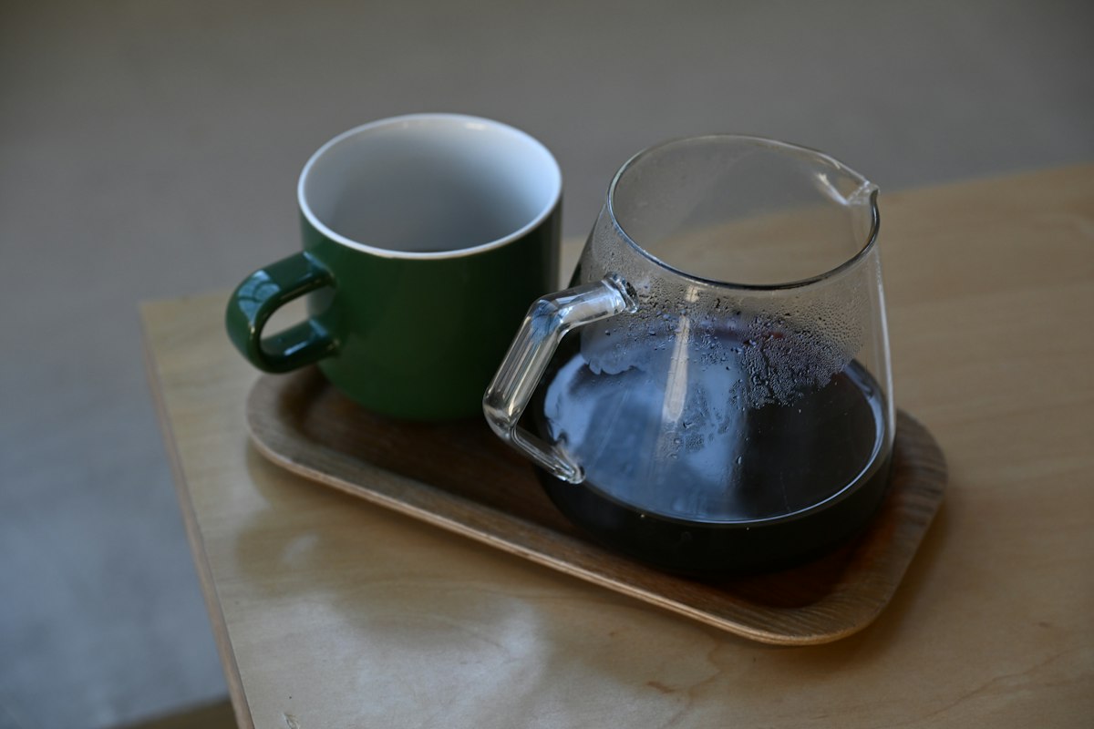 Representative real photo of a glass coffee carafe and green mug on a tray; not the KINTO product